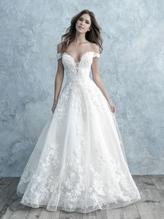 a woman in a white wedding dress standing on a wooden floor with her arms behind her back