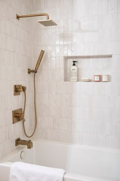 a bath tub with a shower head and hand held faucet