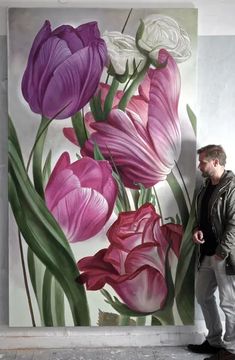 a man standing in front of a painting of purple and white flowers on a wall