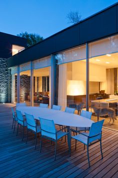 an outdoor dining table and chairs on a wooden deck at night with the lights on