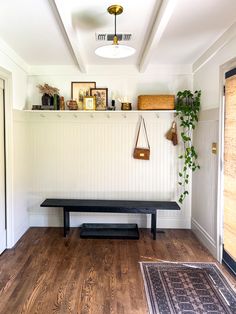 a black bench sitting on top of a hard wood floor next to a wall mounted shelf