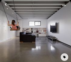 a woman hanging from a rope in a living room next to a couch and television