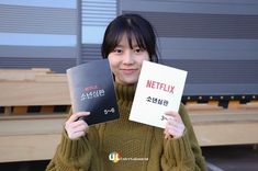 a woman holding two books in front of her face with the words netflix written on them