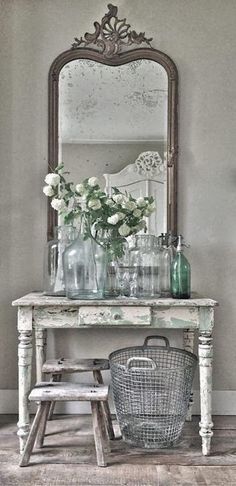 a white table topped with lots of vases and flowers next to a large mirror