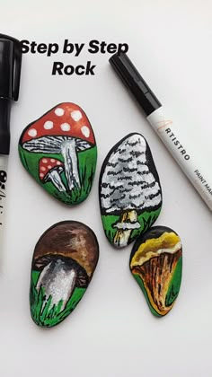 four painted rocks sitting on top of a white table next to a marker and pen