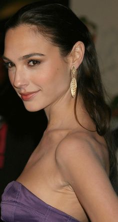 a woman in a strapless purple dress with large gold earrings on her left ear