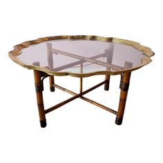 an oval glass table with bamboo legs and gold trimmings on the top, against a white background