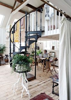 a spiral staircase in the middle of a living room with potted plants on it