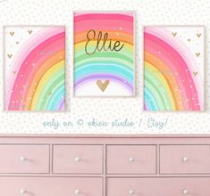 there is a pink dresser with two pictures on the wall and a rainbow in the background