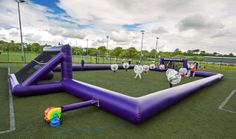 an inflatable slide on top of a green field next to a basketball court