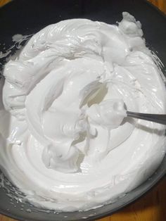 a bowl filled with whipped cream on top of a wooden table