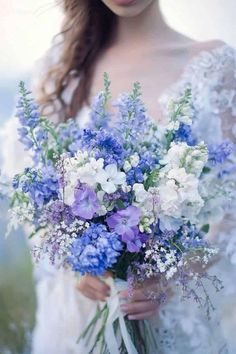 a woman holding a bouquet of blue and white flowers