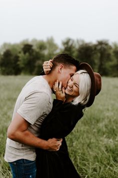 a man and woman hugging in the middle of a field