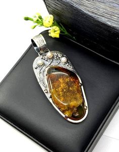 Artisan Amber with pearls pendant  Hand-made Sterling Silver 925.  Stones used: Baltic Cognac Amber, Pearls.  Height -3 2/16” (with bail), Width – 1 3/16”  Height – 80mm, width-30mm.Unique Handcrafted One-of a-kind Design PendantEach Piece of Jewelry in my Collection is Absolutely One of a Kind!When you start wearing a piece of my jewelry you will fall in love with it more and more each day and feel that good Energy and Love that I pass into it while creating this piece of Art.A piece of Art cre Cheap Oxidized Pendant Jewelry, Luxury Amber Pendant Jewelry, Artisan Sterling Silver Pearl Pendant Jewelry, Artisan Sterling Silver Jewelry With Pearl Pendant, Unique Amber Jewelry With Engraving, Elegant Amber Jewelry With Large Pendant, Unique Engraved Amber Jewelry, Fusion Style Cabochon Pendant Necklace, Elegant Amber Rectangular Pendant Jewelry