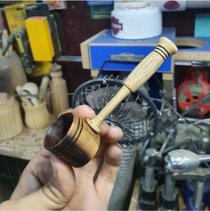 a person holding a small wooden pipe in their hand with other tools behind them on the table