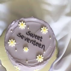 there is a cake that says sweet seventien on the top and daisies on the bottom