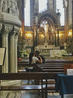 two people sitting on pews in a church with an ornate alter and stained glass windows