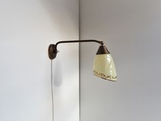 a wall mounted light on the side of a white wall next to a lamp shade