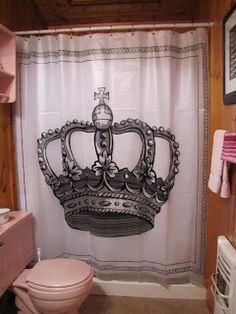 a bathroom with a toilet, sink and shower curtain that has a crown on it