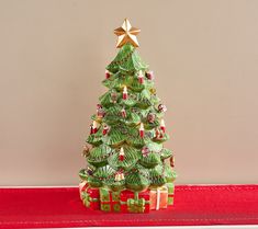 a green christmas tree sitting on top of a red table