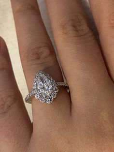 a woman's hand with a diamond ring on top of her finger and an engagement band