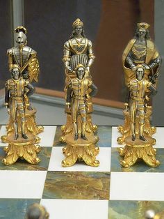 gold and silver figurines sitting on top of a chess board