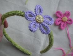 crocheted flower headbands are being held by a person's hand