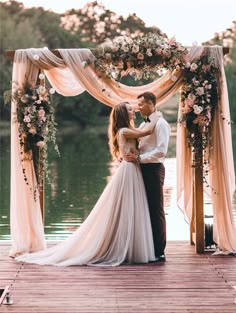 a bride and groom standing under an arch with flowers on it at the end of their wedding ceremony