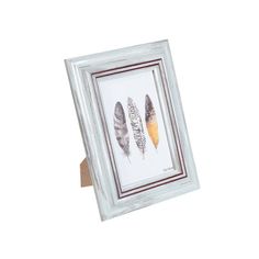 a white frame with three feathers in it