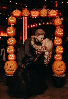 a man and woman kissing in front of pumpkins on display at a halloween party