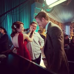 a man and woman standing next to each other in front of a piano at a party