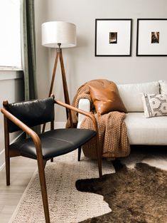 a white couch sitting in a living room next to a chair and rug on top of a hard wood floor