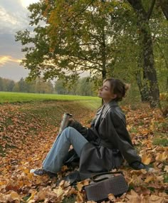 a woman sitting on the ground in leaves with her eyes closed and looking up into the sky