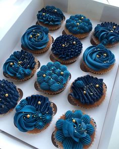 twelve blue cupcakes in a white box with gold decorations