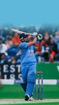 a man swinging a bat on top of a green field in front of a crowd