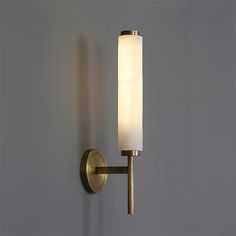 a wall light that is on the side of a wall with a white glass shade