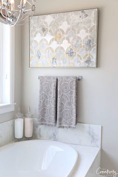 a bathroom with a chandelier and two towels hanging on the wall above the bathtub