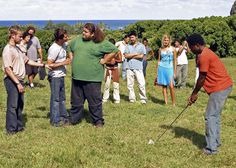 a group of people standing on top of a grass covered field next to each other