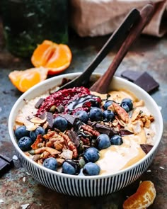 a bowl of oatmeal with blueberries, walnuts and orange slices