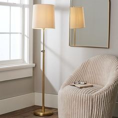 a living room with a chair, lamp and mirror on the wall next to it