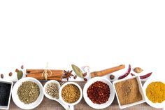 various spices are arranged in white bowls on a table