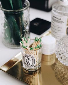 some green and white matchesticks in a glass on a tray next to other items