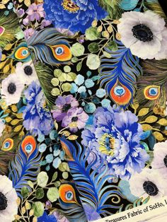 a close up view of the fabric with flowers and peacocks on it, as well as feathers