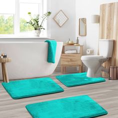 two bathroom rugs on the floor in front of a bathtub