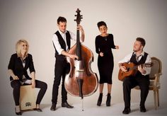 three people are posing for a photo with an instrument in front of them and one person is sitting on a chair