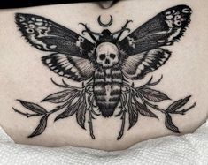 a woman's stomach with a black and white moth tattoo on the side of her belly