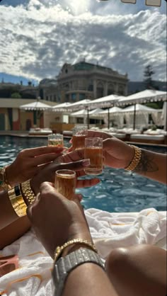 several people are toasting with drinks by the pool