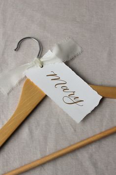 a pair of wooden clothes hangers with personalized tags on them