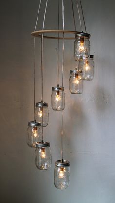 mason jar chandelier with lights hanging from the ceiling in front of a wall