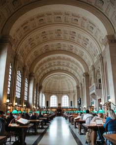 the interior of a large library with tables and lamps on either side of the room